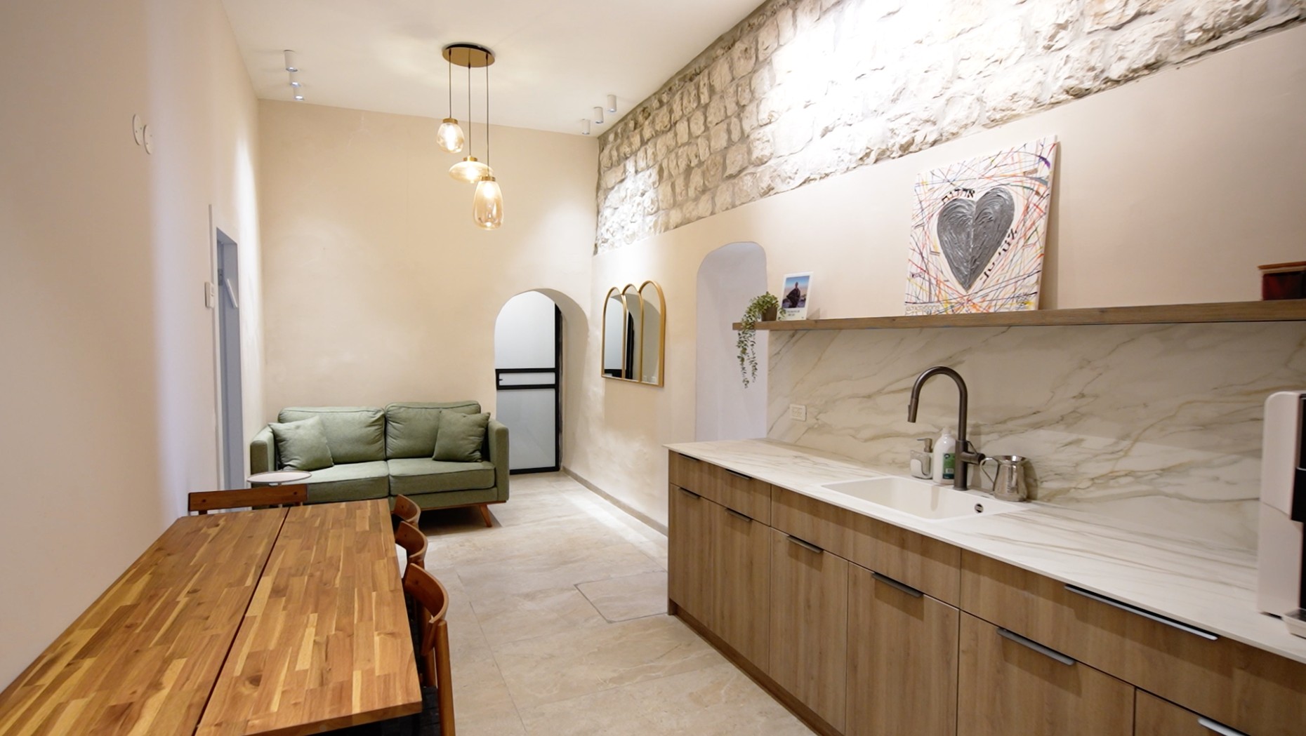 Beit Binyamin’s living and kitchen space with its original stone wall